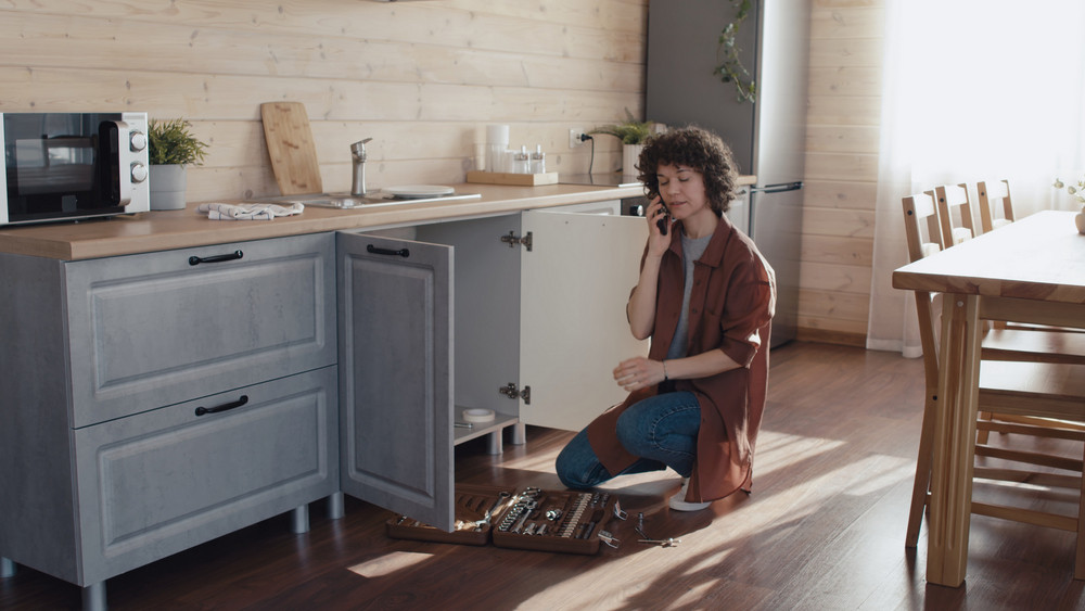 Plumbing company helping woman on phone with kitchen sink plumbing issue